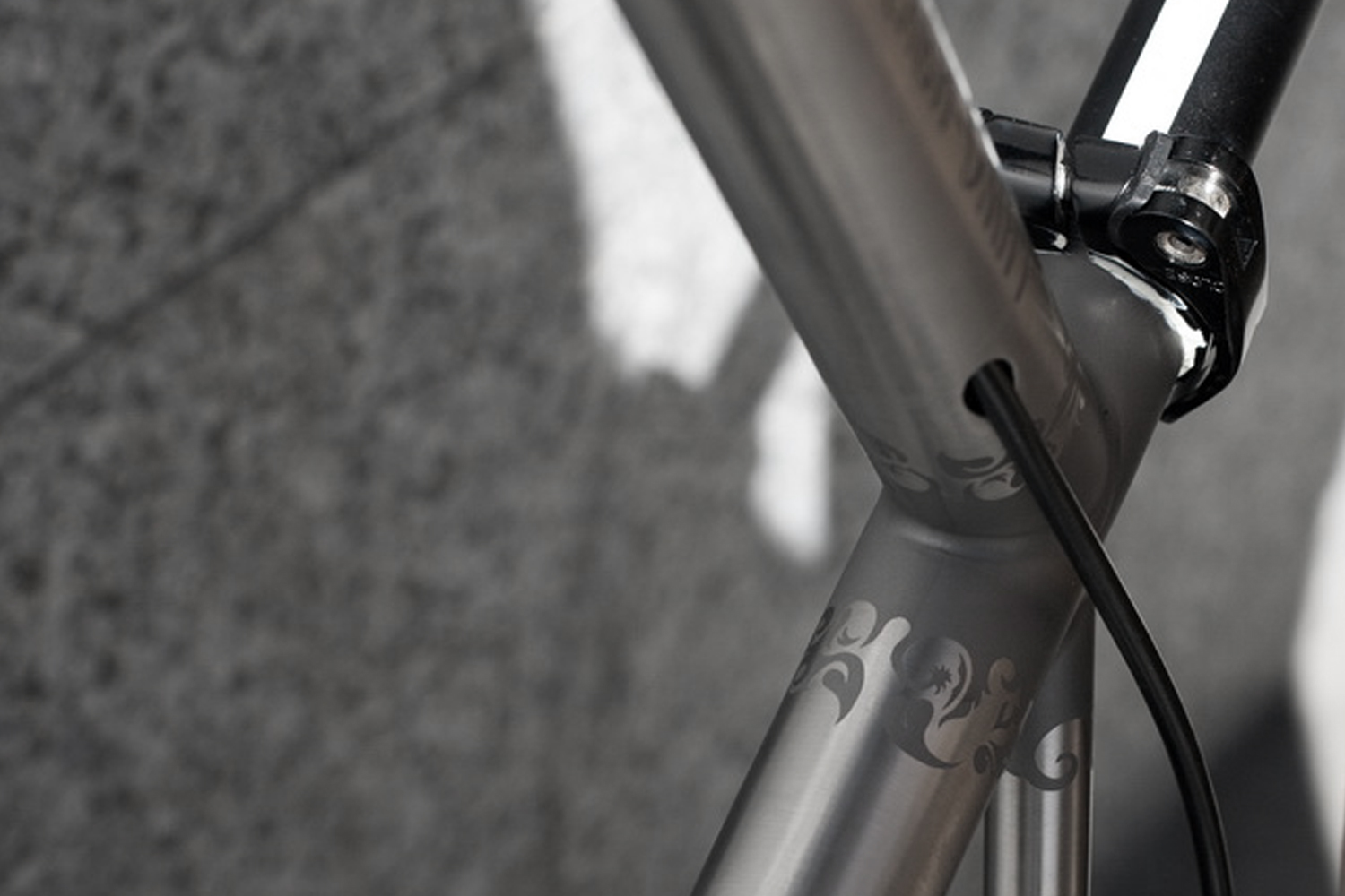 Hand-drawn vector flourishes on a titanium tube beside a cable port